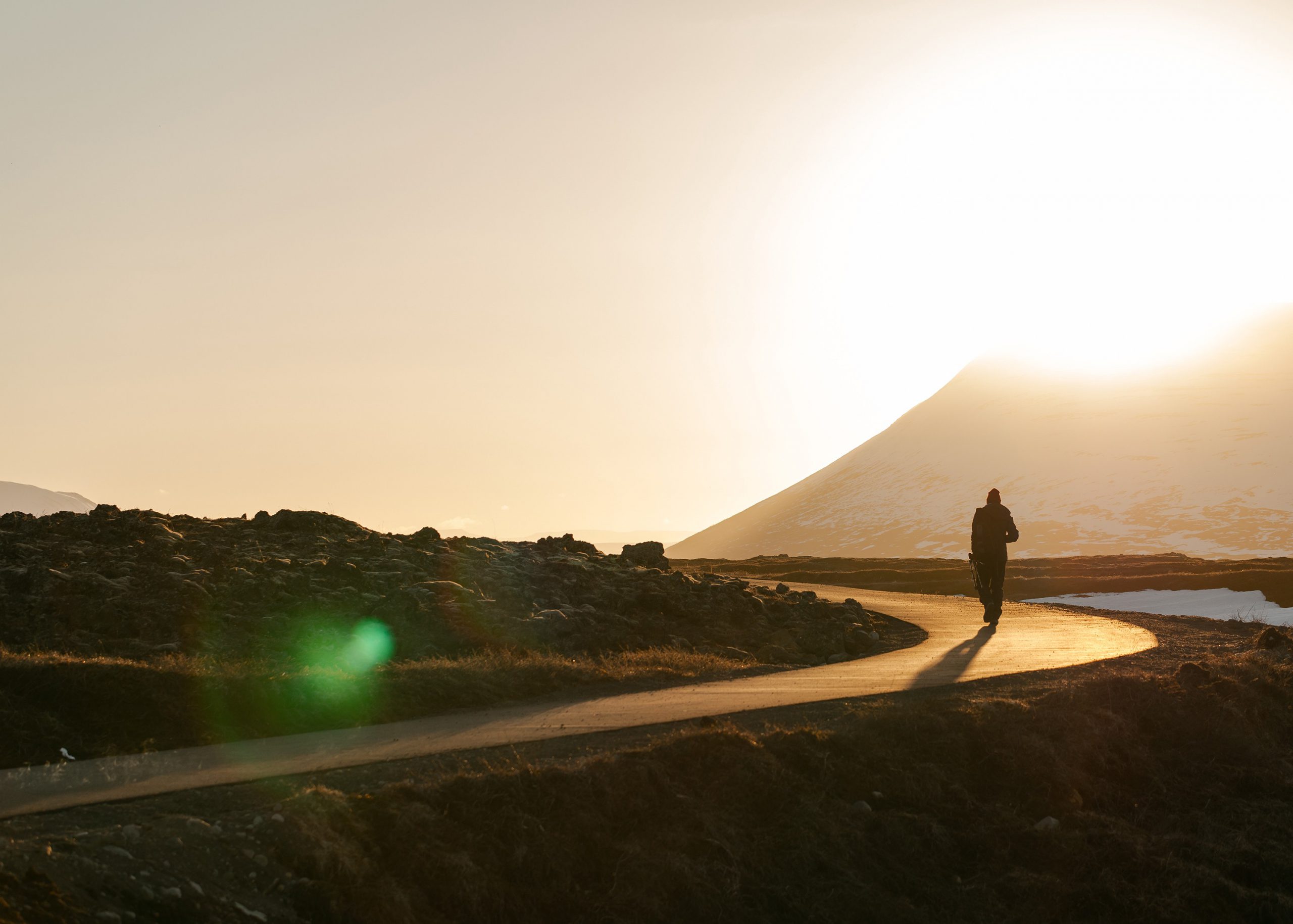 person running on the road infront of a mountain during sunrise